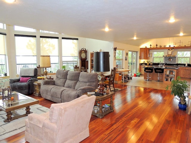 kitchen with stainless steel refrigerator, light tile flooring, backsplash, an island with sink, and pendant lighting