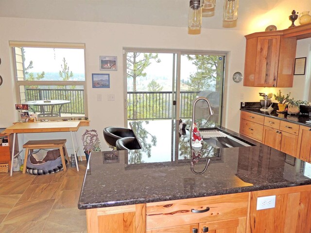 35025 Mourning Dove Ln N, Davenport, WA 99122 - kitchen with a sink, dark stone counters, a kitchen island with sink, and decorative light fixtures