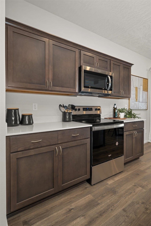 kitchen featuring appliances with stainless steel finishes, dark hardwood / wood-style flooring, and dark brown cabinetry