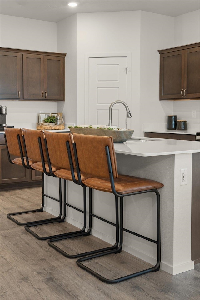 kitchen featuring dark brown cabinets, a kitchen breakfast bar, and light hardwood / wood-style floors