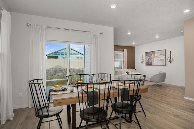 dining room featuring wood-type flooring and a textured ceiling