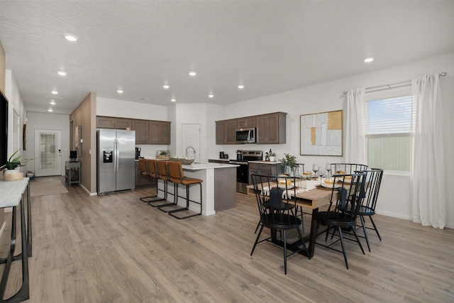 dining room featuring light wood-type flooring, a textured ceiling, and sink