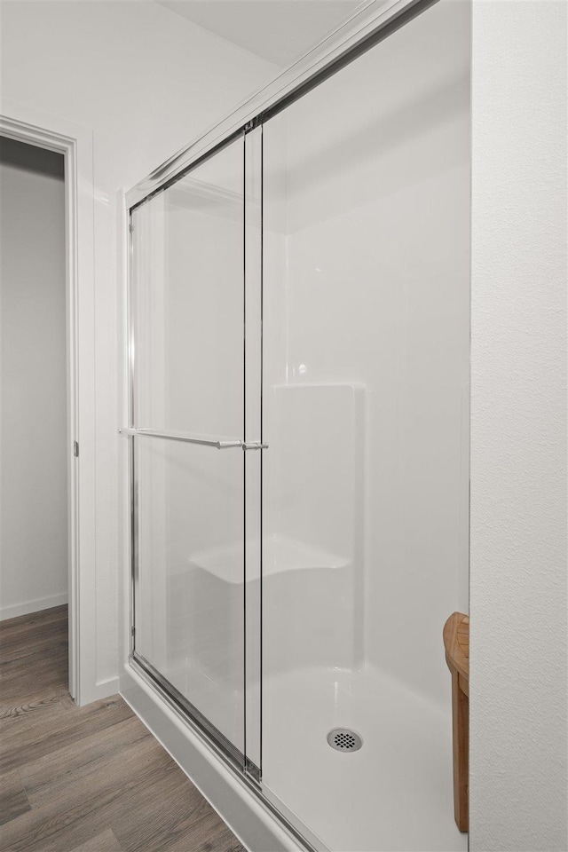 bathroom with wood-type flooring and a shower with door