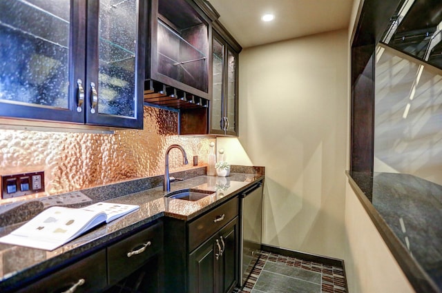 bar featuring dark brown cabinetry, sink, dishwasher, and dark stone counters