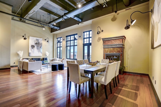 dining room featuring track lighting, dark hardwood / wood-style flooring, and a high ceiling