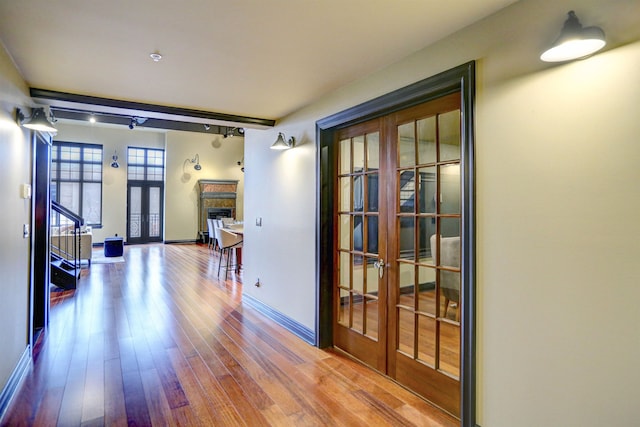 hall with wood-type flooring and french doors