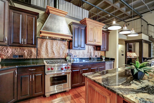 kitchen featuring pendant lighting, backsplash, custom range hood, stainless steel appliances, and sink