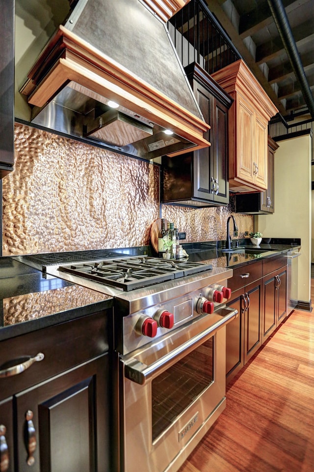 kitchen with backsplash, light hardwood / wood-style flooring, premium range, custom range hood, and dark stone counters