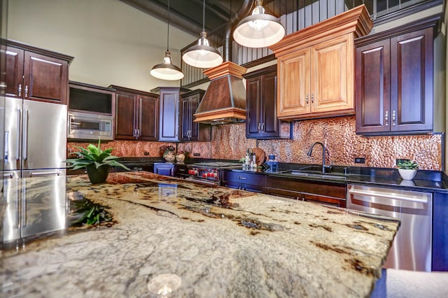 kitchen featuring high end appliances, custom range hood, tasteful backsplash, sink, and pendant lighting