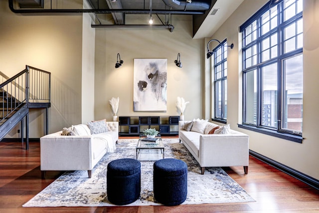 living room with dark wood-type flooring and a high ceiling