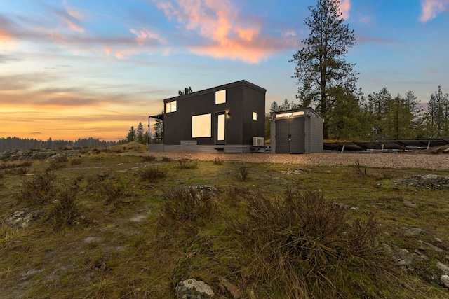 back of house at dusk with an outbuilding and a shed