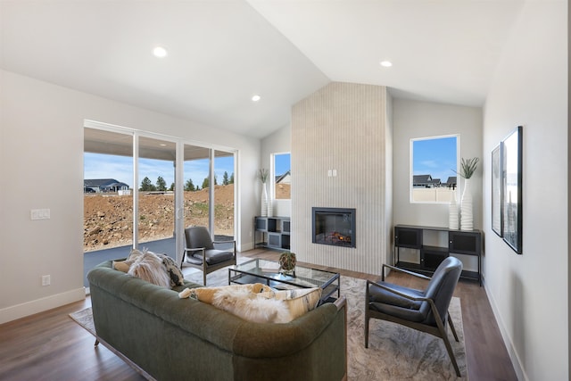 living room featuring hardwood / wood-style flooring, lofted ceiling, and a large fireplace