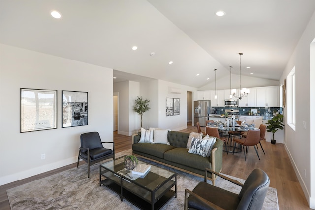 living room featuring vaulted ceiling, a chandelier, and light hardwood / wood-style flooring