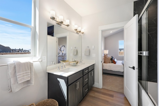 bathroom featuring hardwood / wood-style flooring, vanity, and shower / bath combination with glass door