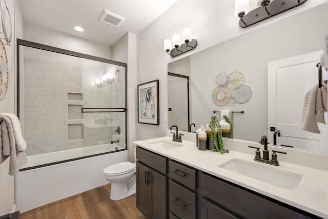 full bathroom with vanity, hardwood / wood-style flooring, enclosed tub / shower combo, and toilet