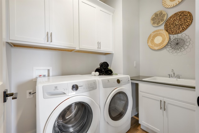 clothes washing area featuring cabinets, wood-type flooring, washer and clothes dryer, and sink