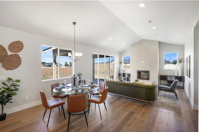 dining space featuring vaulted ceiling, dark wood-type flooring, a wealth of natural light, and a fireplace