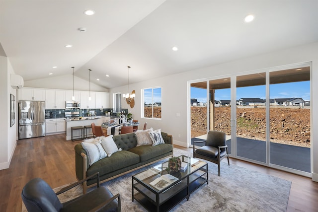 living room with dark wood-type flooring, vaulted ceiling, a wall unit AC, and a notable chandelier