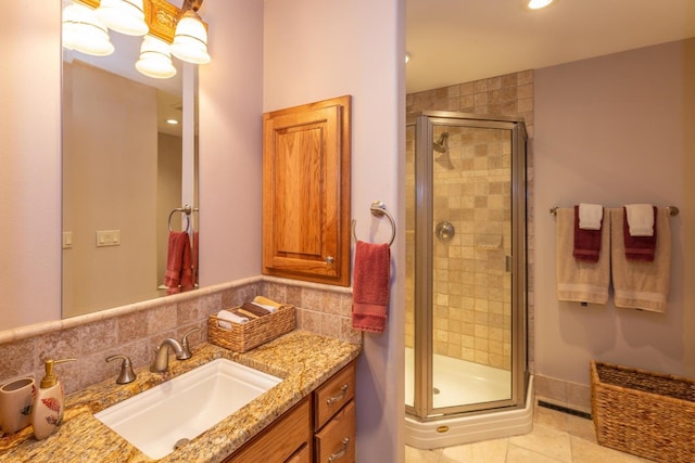 bathroom featuring backsplash, a shower with door, tile floors, and vanity