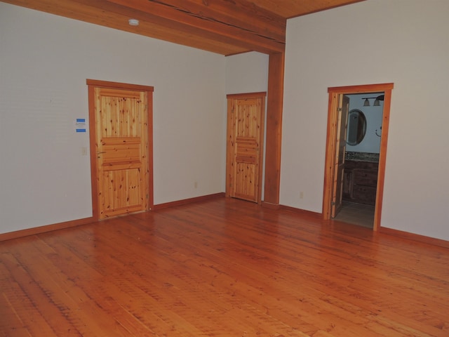 empty room with wooden ceiling, hardwood / wood-style floors, and beam ceiling