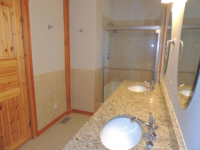 bathroom with dual vanity, an enclosed shower, and tile floors