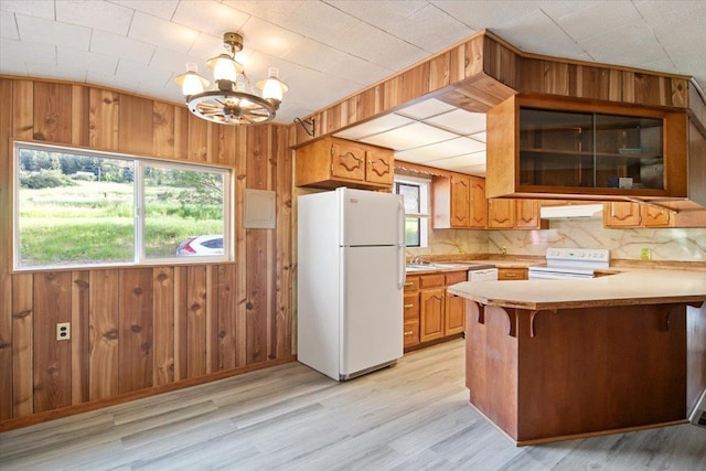 kitchen featuring kitchen peninsula, a healthy amount of sunlight, white appliances, and a notable chandelier