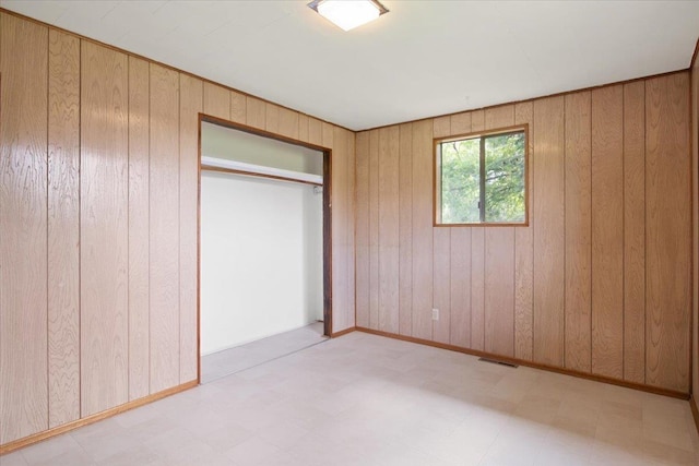 unfurnished bedroom featuring a closet and wooden walls