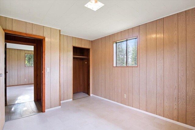 unfurnished bedroom with wood walls and a closet