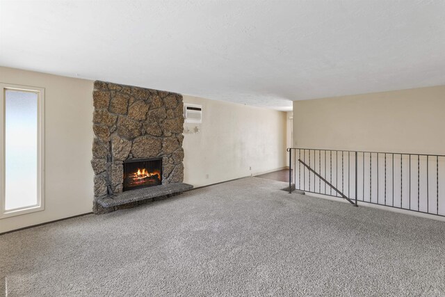 unfurnished living room featuring a stone fireplace, a healthy amount of sunlight, and carpet floors