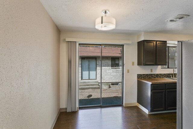 kitchen featuring wood-type flooring, sink, stainless steel refrigerator, and a textured ceiling