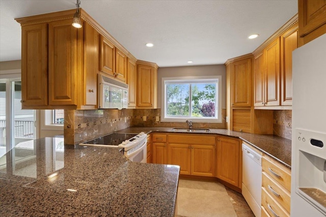 kitchen featuring white appliances, tasteful backsplash, dark stone countertops, and sink