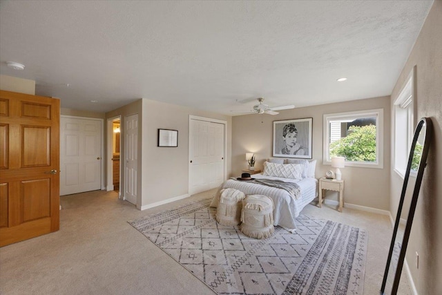 bedroom featuring a textured ceiling, light colored carpet, and ceiling fan