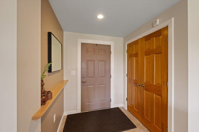 doorway to outside featuring light tile patterned floors and a textured ceiling