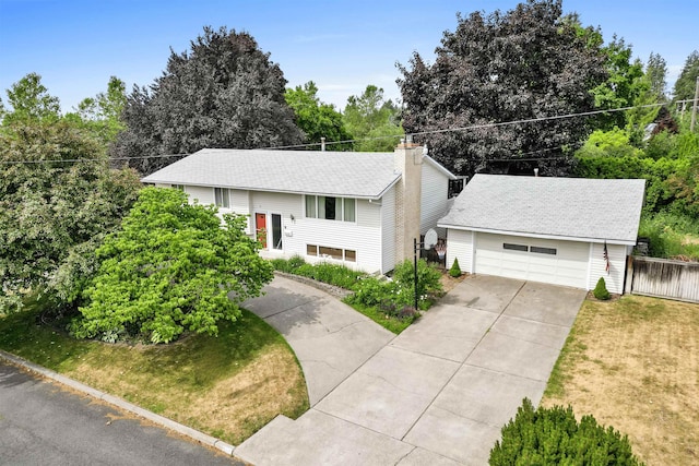 bi-level home featuring a front lawn, a chimney, an outdoor structure, and fence