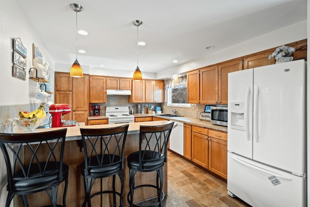 kitchen featuring pendant lighting, a sink, a peninsula, white appliances, and under cabinet range hood