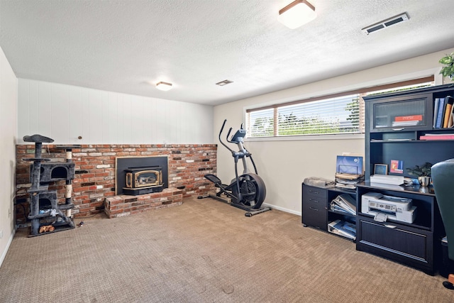 exercise area with a wood stove, carpet floors, visible vents, and a textured ceiling