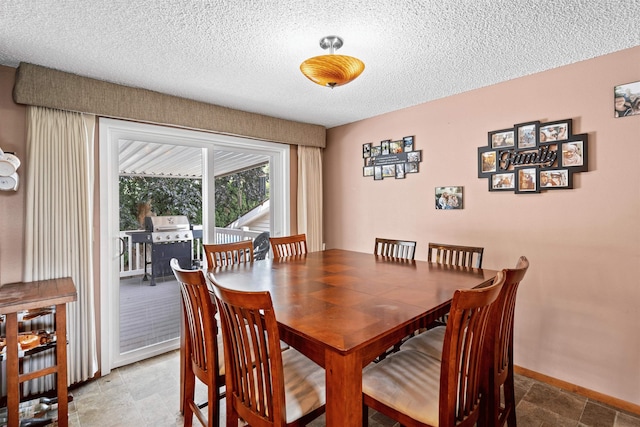 dining room featuring stone finish flooring, a textured ceiling, and baseboards