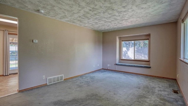 carpeted empty room featuring a textured ceiling