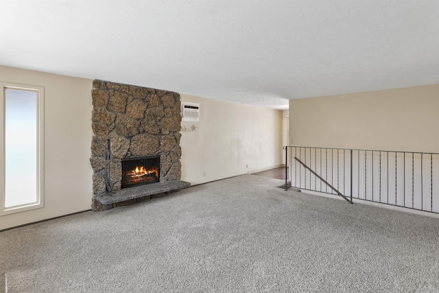 unfurnished living room featuring a stone fireplace, a healthy amount of sunlight, and carpet floors