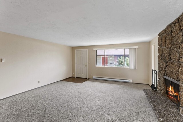 unfurnished living room featuring a fireplace, carpet, baseboard heating, and a textured ceiling