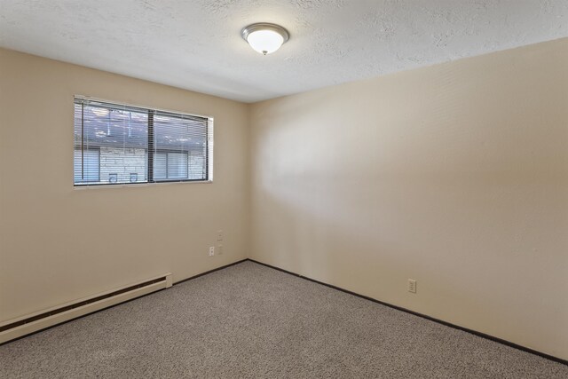 carpeted spare room with baseboard heating and a textured ceiling