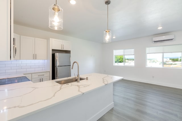 kitchen featuring stainless steel fridge, sink, backsplash, decorative light fixtures, and hardwood / wood-style flooring