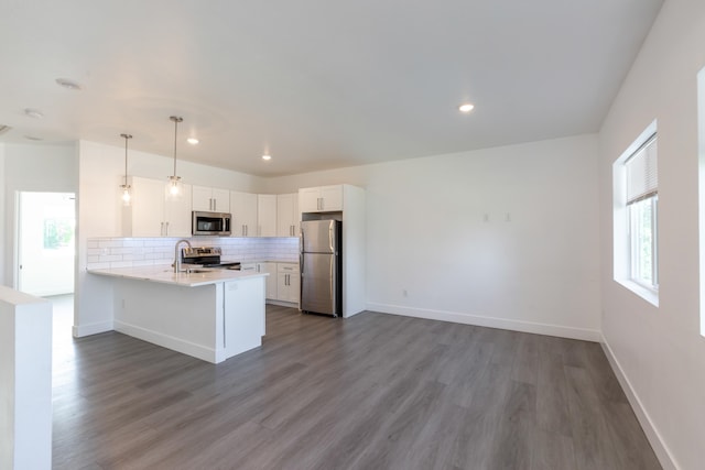 kitchen featuring white cabinets, appliances with stainless steel finishes, kitchen peninsula, backsplash, and dark wood-type flooring