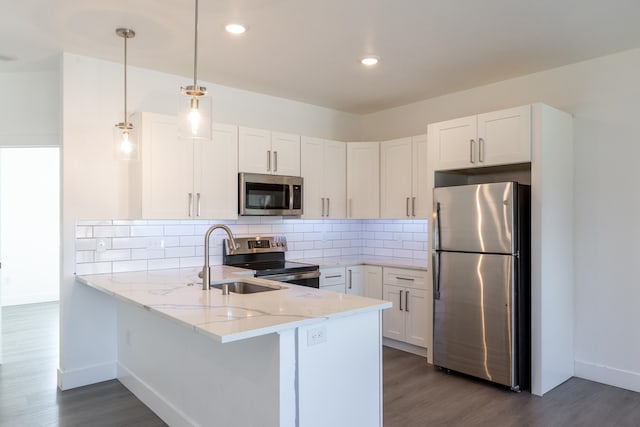 kitchen with stainless steel appliances, white cabinets, pendant lighting, kitchen peninsula, and dark wood-type flooring