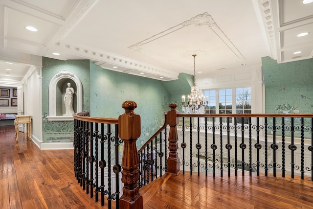 corridor with an inviting chandelier, crown molding, wood-type flooring, and coffered ceiling