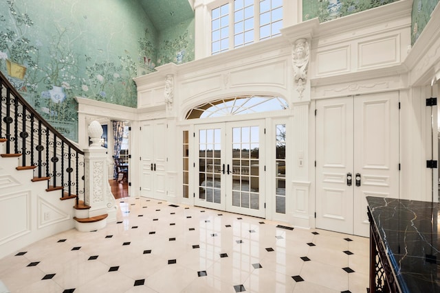 entryway featuring french doors, light tile patterned floors, and a towering ceiling