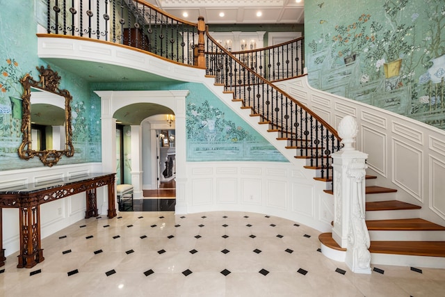 stairway featuring a high ceiling, coffered ceiling, and light tile patterned floors