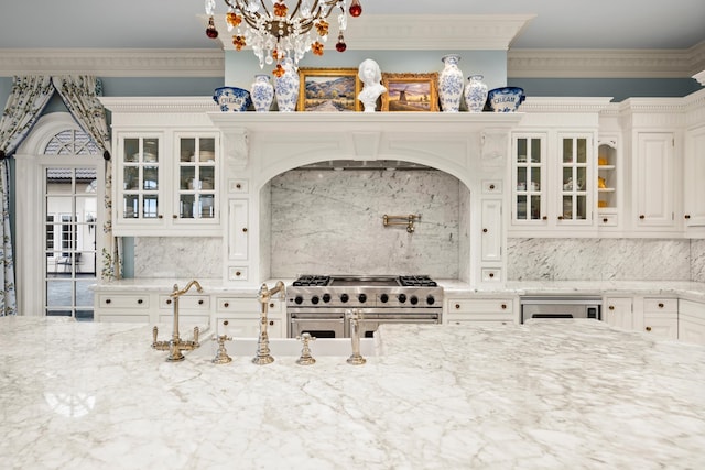 kitchen featuring crown molding, range with two ovens, a chandelier, and white cabinets