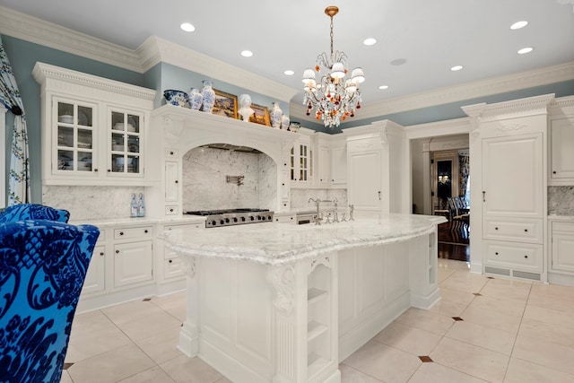 kitchen featuring white cabinets, pendant lighting, backsplash, a kitchen island with sink, and light tile patterned flooring