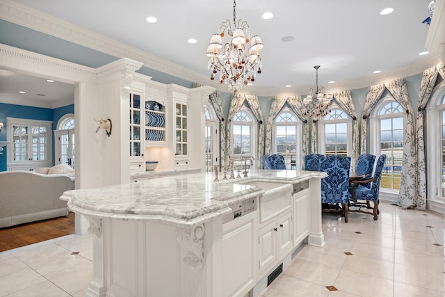 kitchen with white cabinets, decorative light fixtures, crown molding, and light wood-type flooring